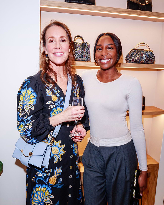 Two women standing next to each other holding wine glasses
