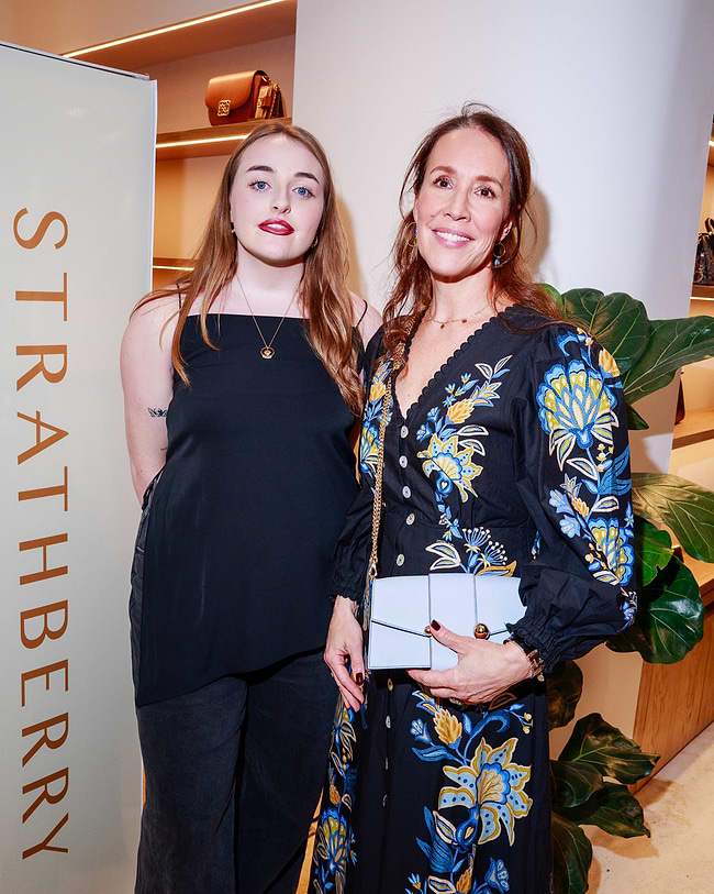Two women standing next to each other in front of a sign