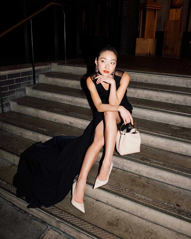 A woman in a black dress sitting on some steps