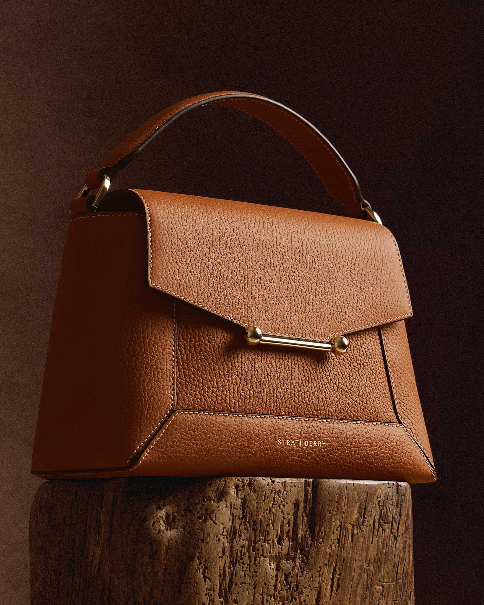 A brown purse sitting on top of a wooden stump