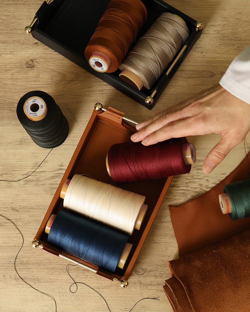 A person holding a spool of thread next to a box of spools