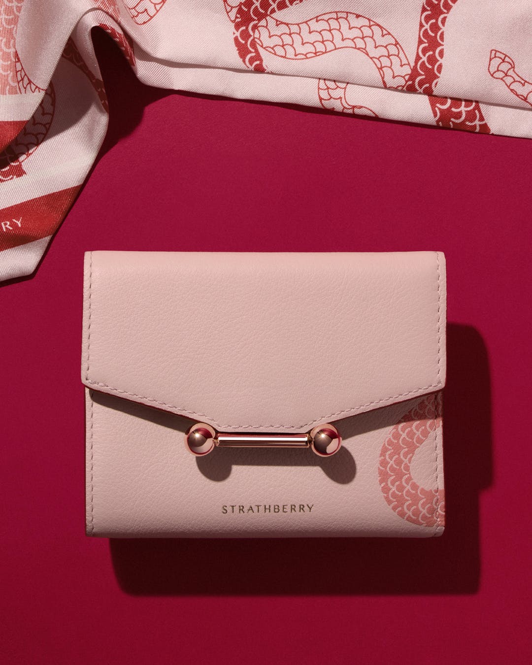 A pink wallet and a pink and white scarf