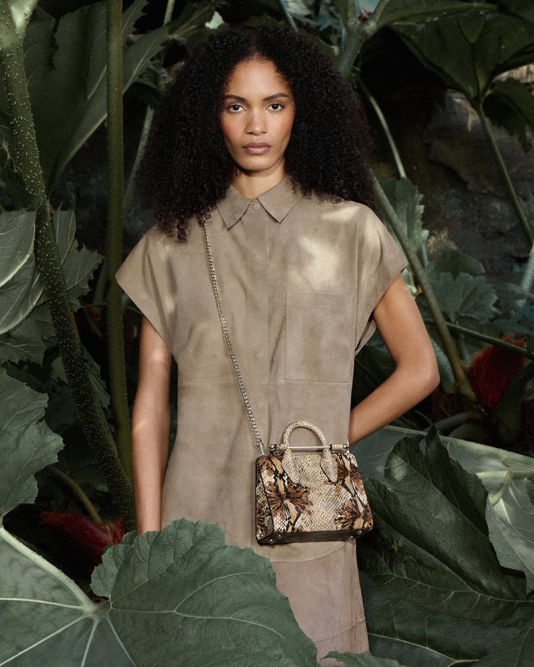 A woman with a handbag standing in front of plants