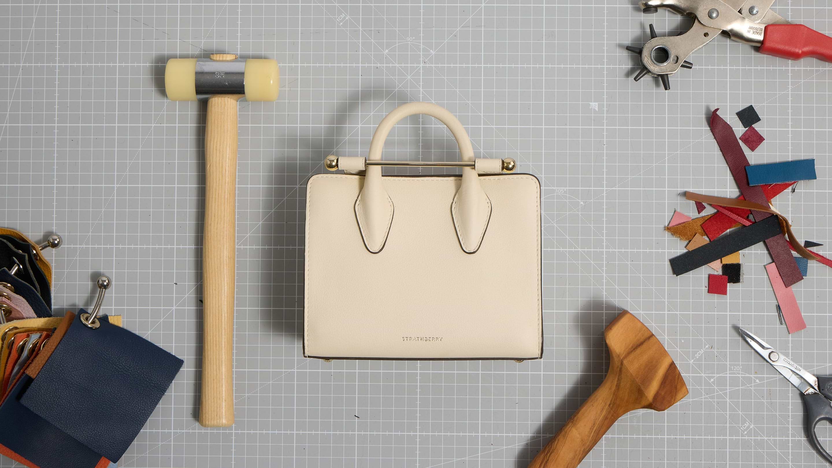 A white purse sitting on top of a table next to a hammer