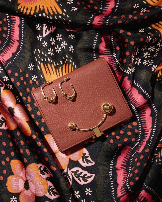 A pink purse sitting on top of a colorful cloth