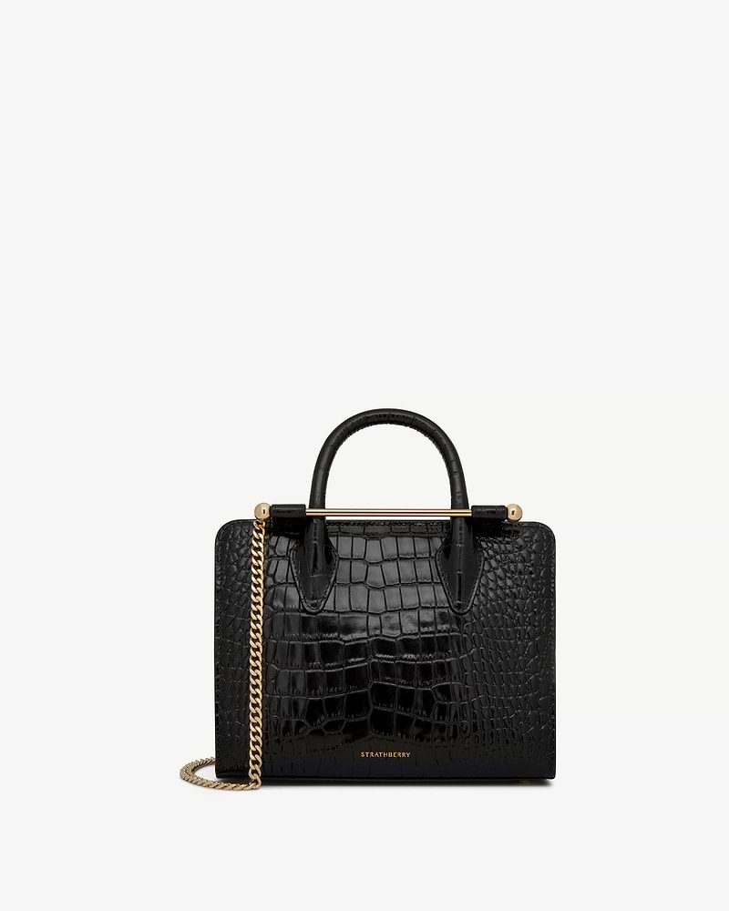 Black croc mini tote with top handles, gold bar detail and chain, Strathberry logo.