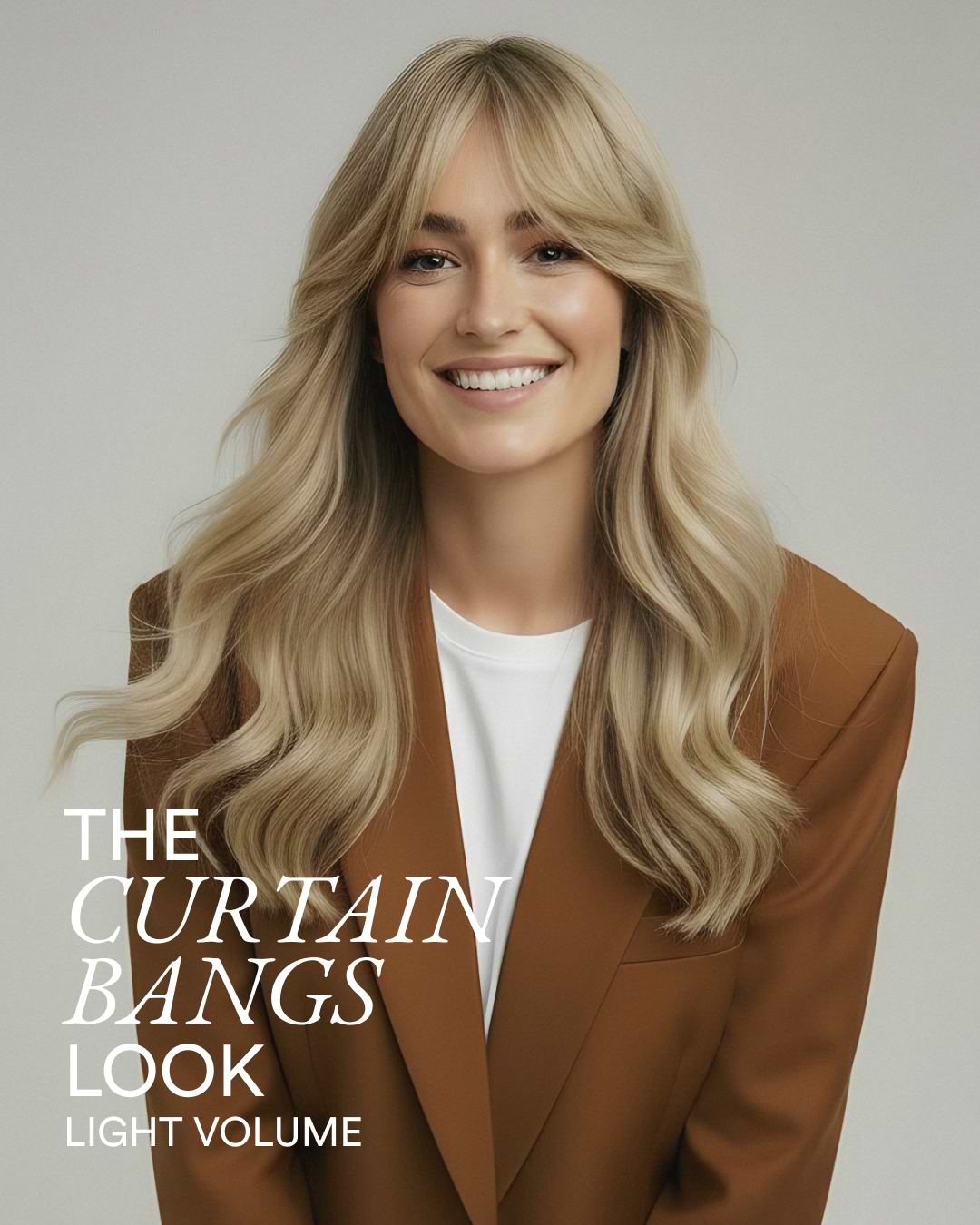 Smiling woman with long wavy blonde curtain bangs, wearing a brown blazer over a white top; ad text: "The Curtain Bangs Look."