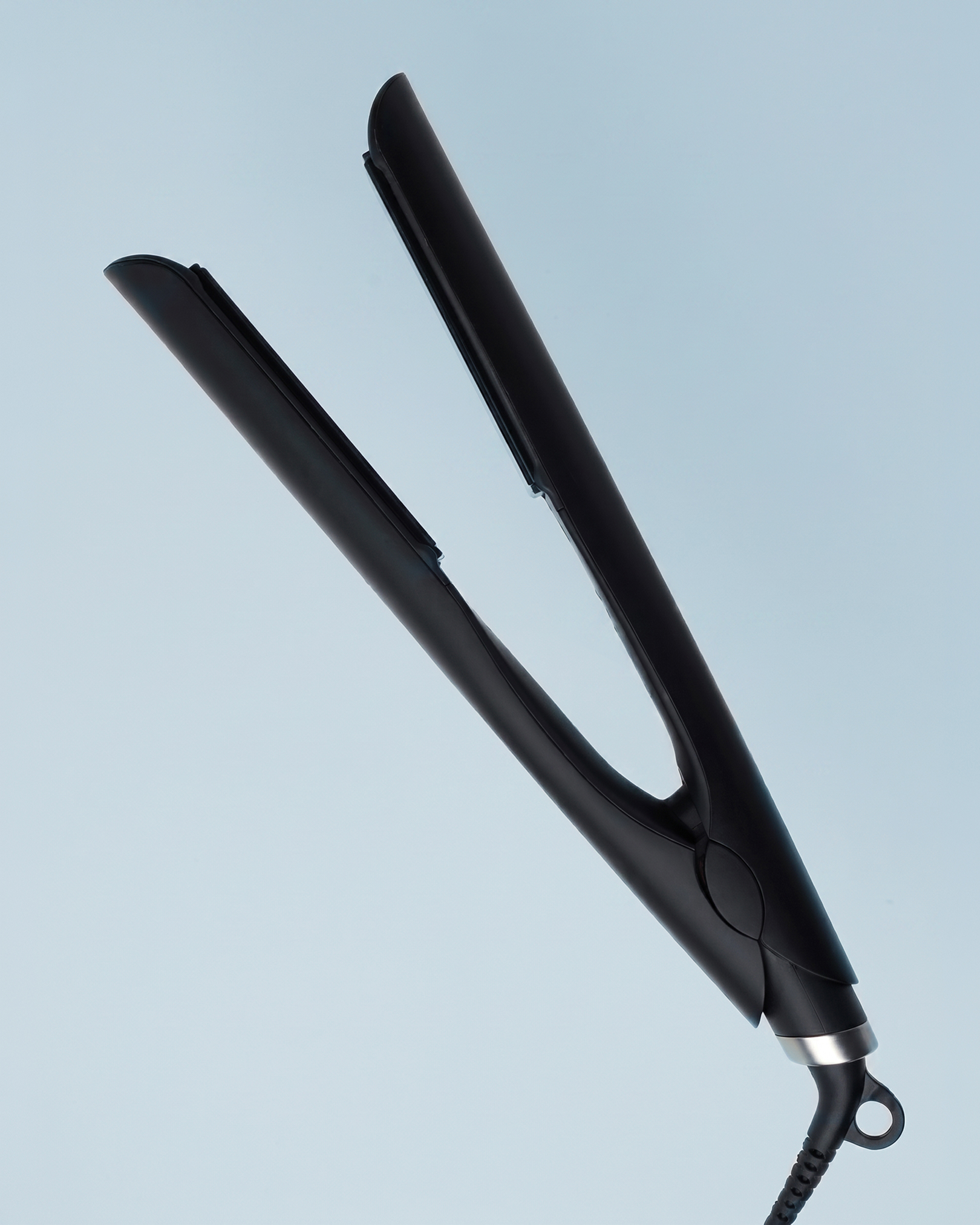 A black hair straightener with metallic accents, slightly open, against a light blue background.