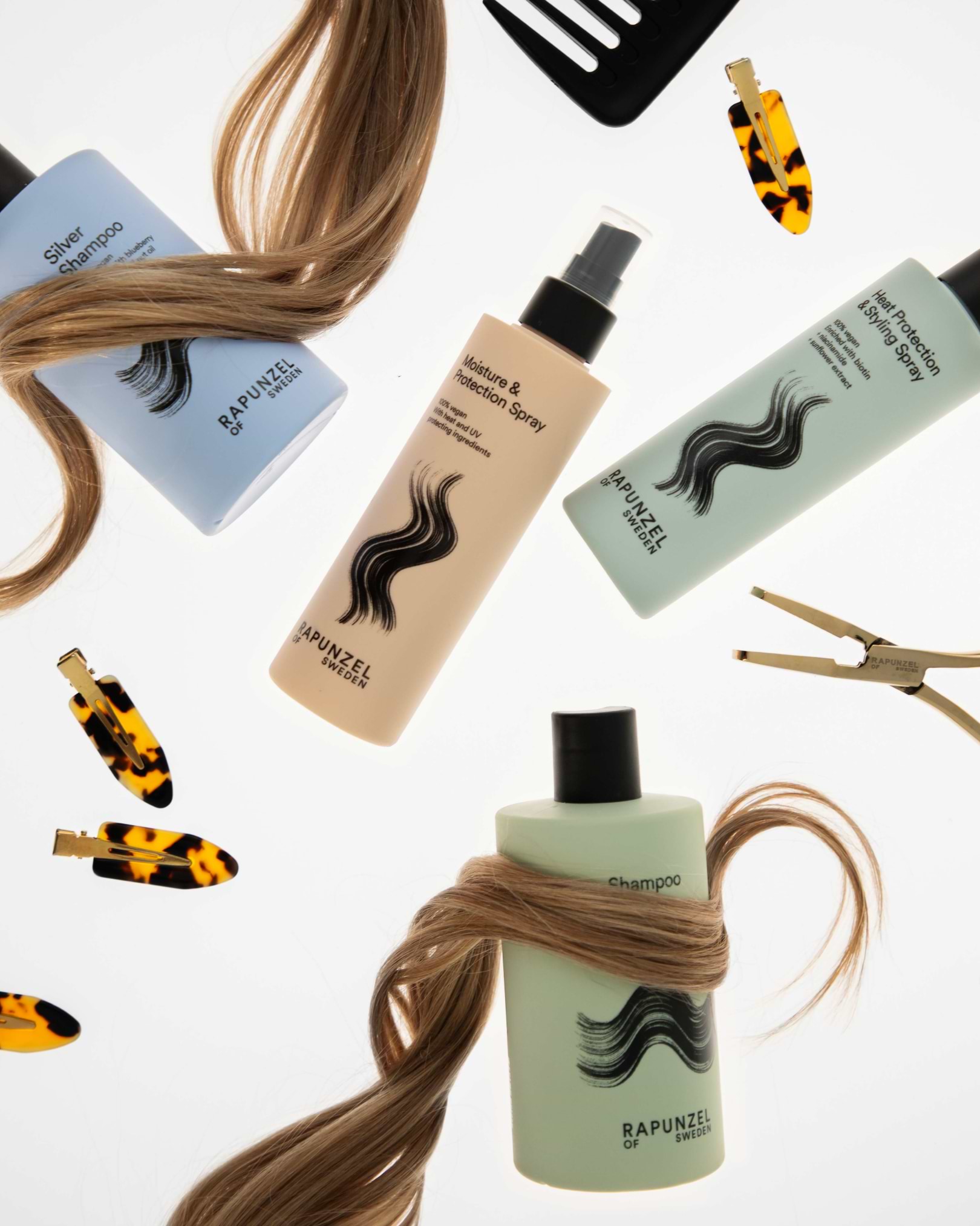 Hair care products with flowing hair strands, including shampoo, conditioner, and spray bottles, surrounded by tortoiseshell hair clips.