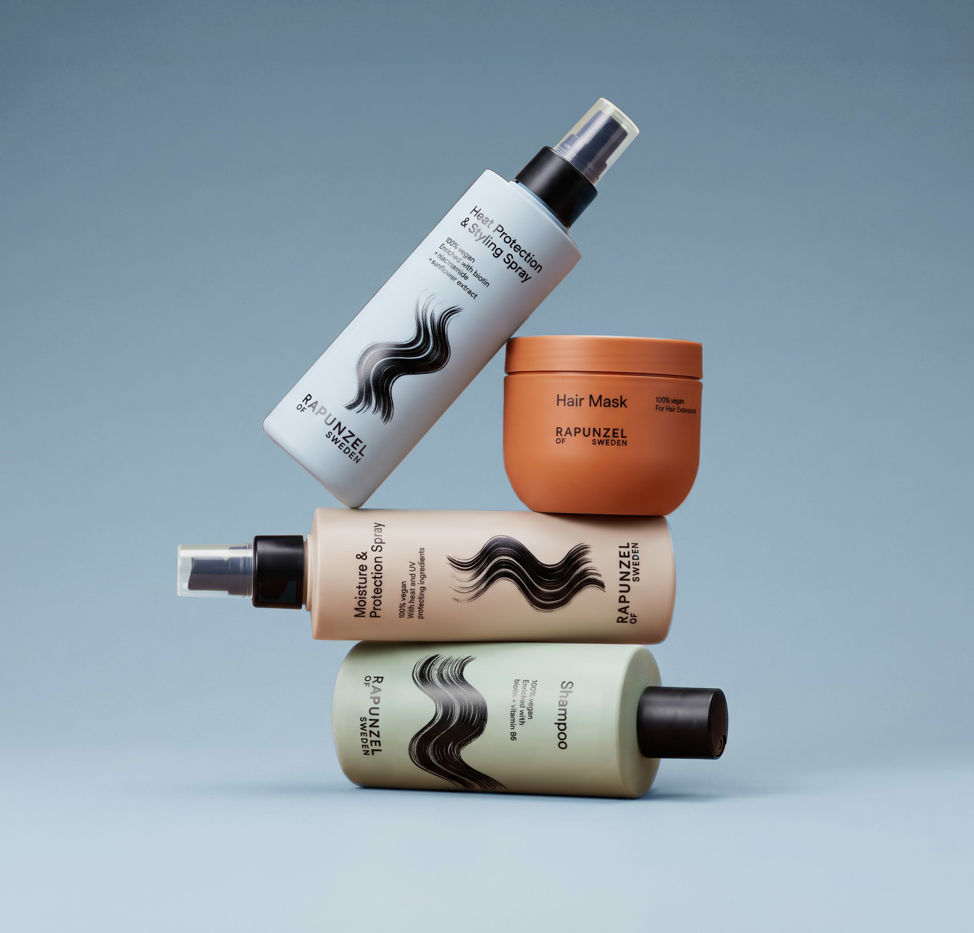 Four Rapunzel of Sweden hair care products, including shampoo, hair mask, and styling sprays, stacked artfully against a blue background.
