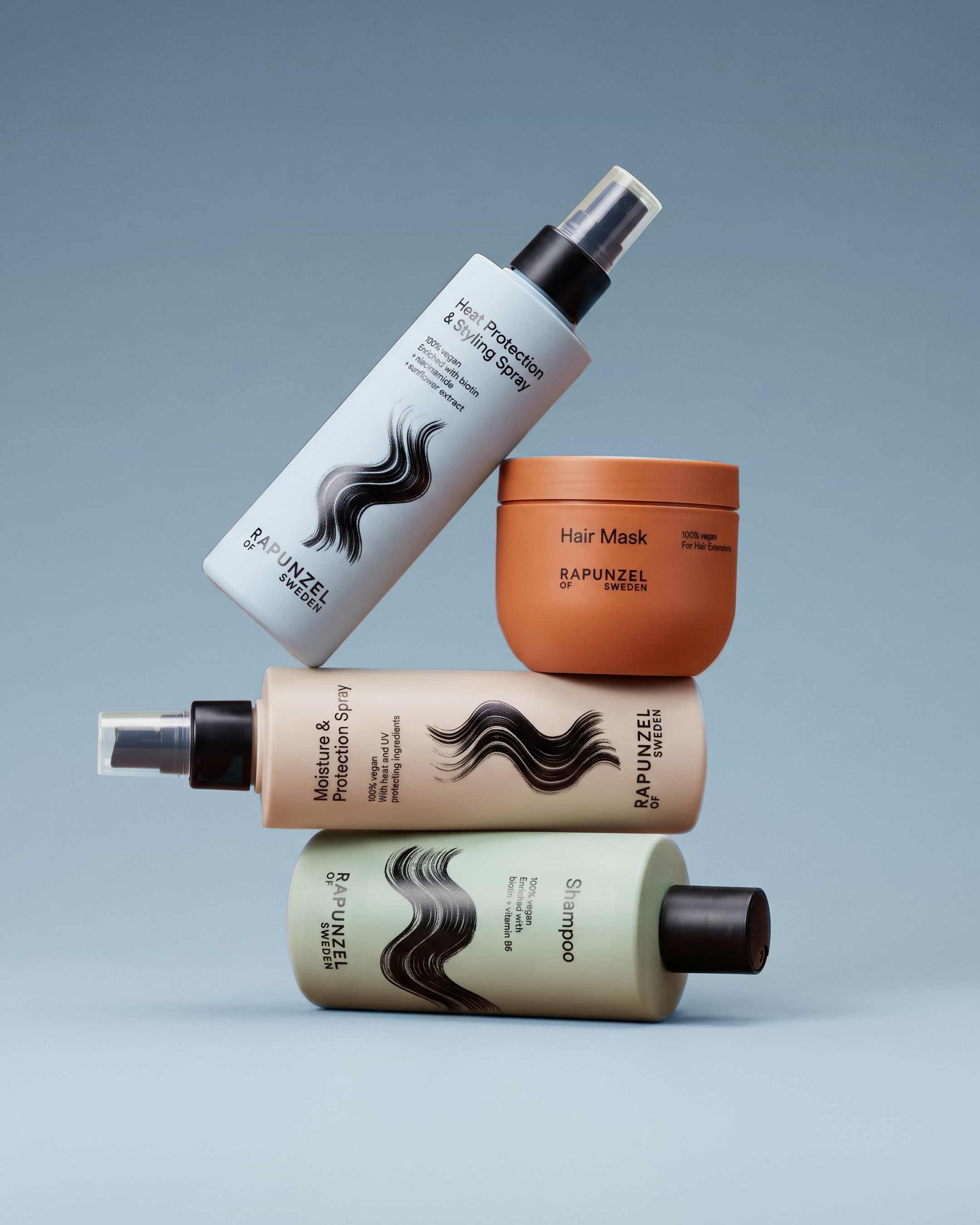 Four Rapunzel of Sweden hair products, including sprays and a hair mask, displayed against a blue background.