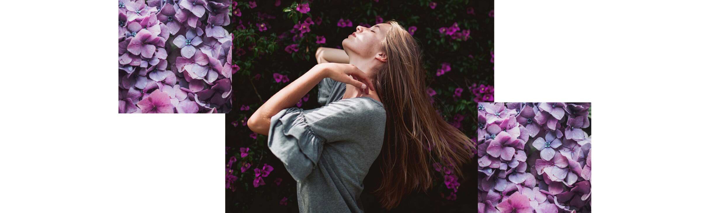 Woman with long hair extensions, tilts her head back joyfully, surrounded by purple and pink flowers.