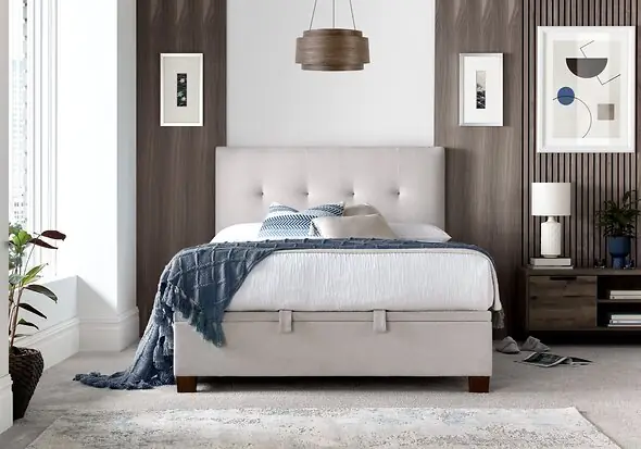 Luxurious pale cream fabric ottoman bed frame with modern dark wooden feet.