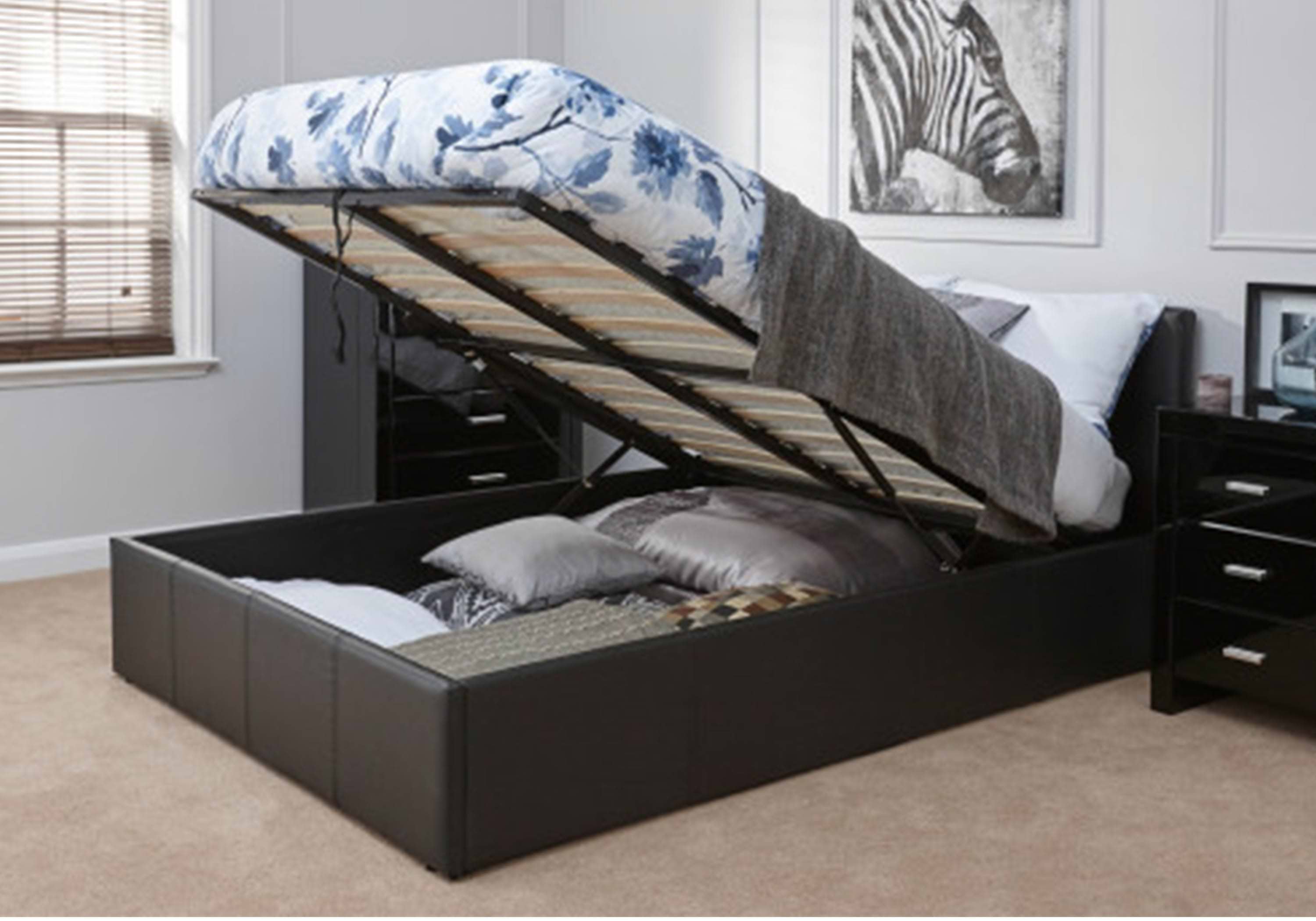 Brown small double ottoman bed with white and blue flowery patterned bedsheets. The mattress has been lifted to reveal the storage space underneath
