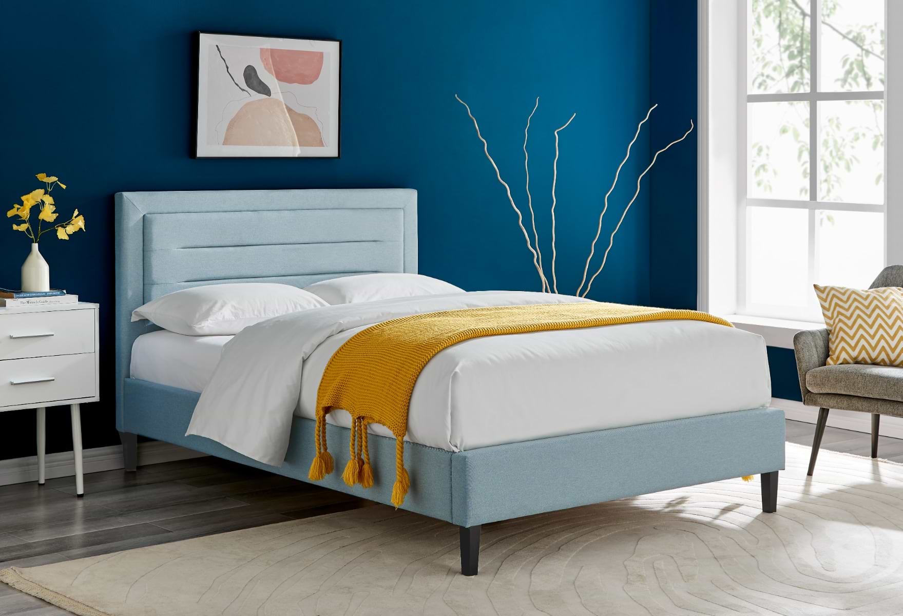 Blue double bed with white and yellow bedsheets, against blue bedroom wall