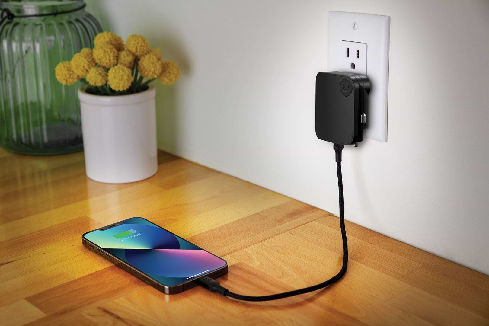 iphone charging via Scoshce cable and travel charger plugged into wall outlet while sitting on countertop
