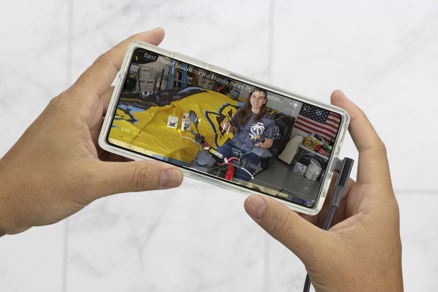 hands holding Note20 phone with video playing and right angle cable connected