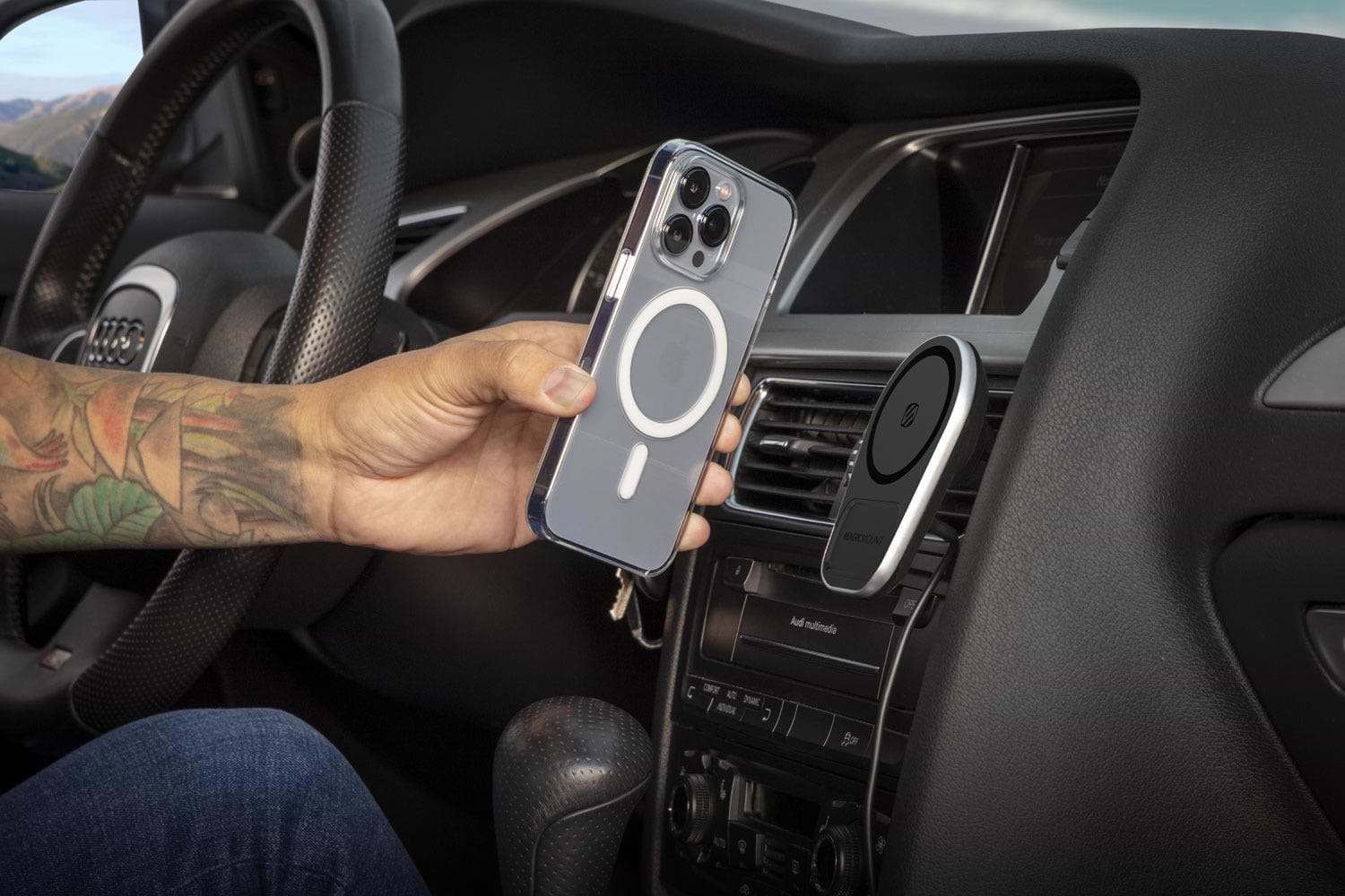Man hovering iphone13 over Scosche wireless charger on car vent