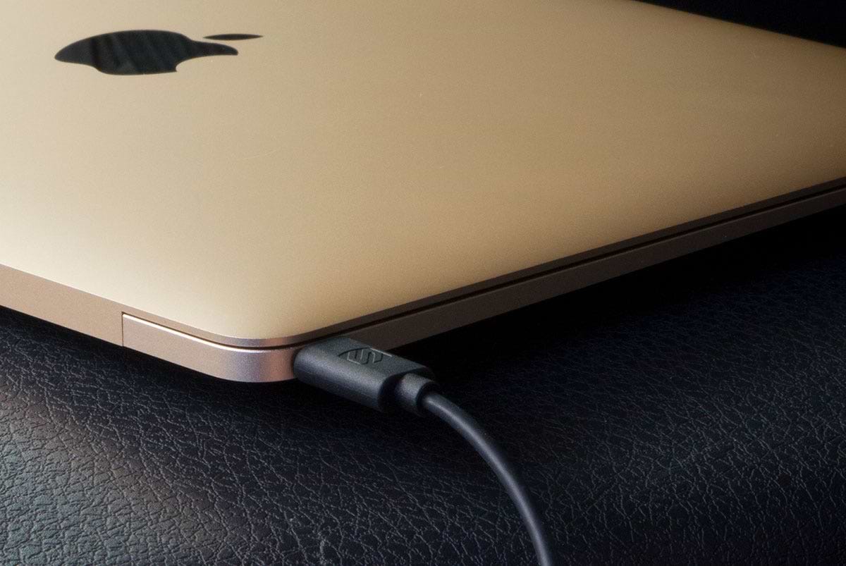 gold colored MacBook connected to Scosche USB-C cable on leather surface