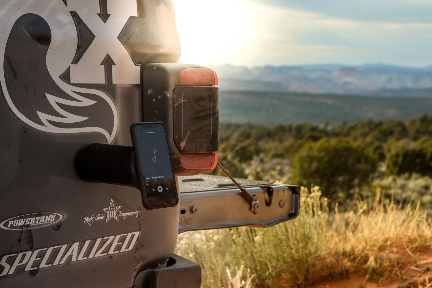iphone playing music through magnetic speaker mounted to truck bed side along trail