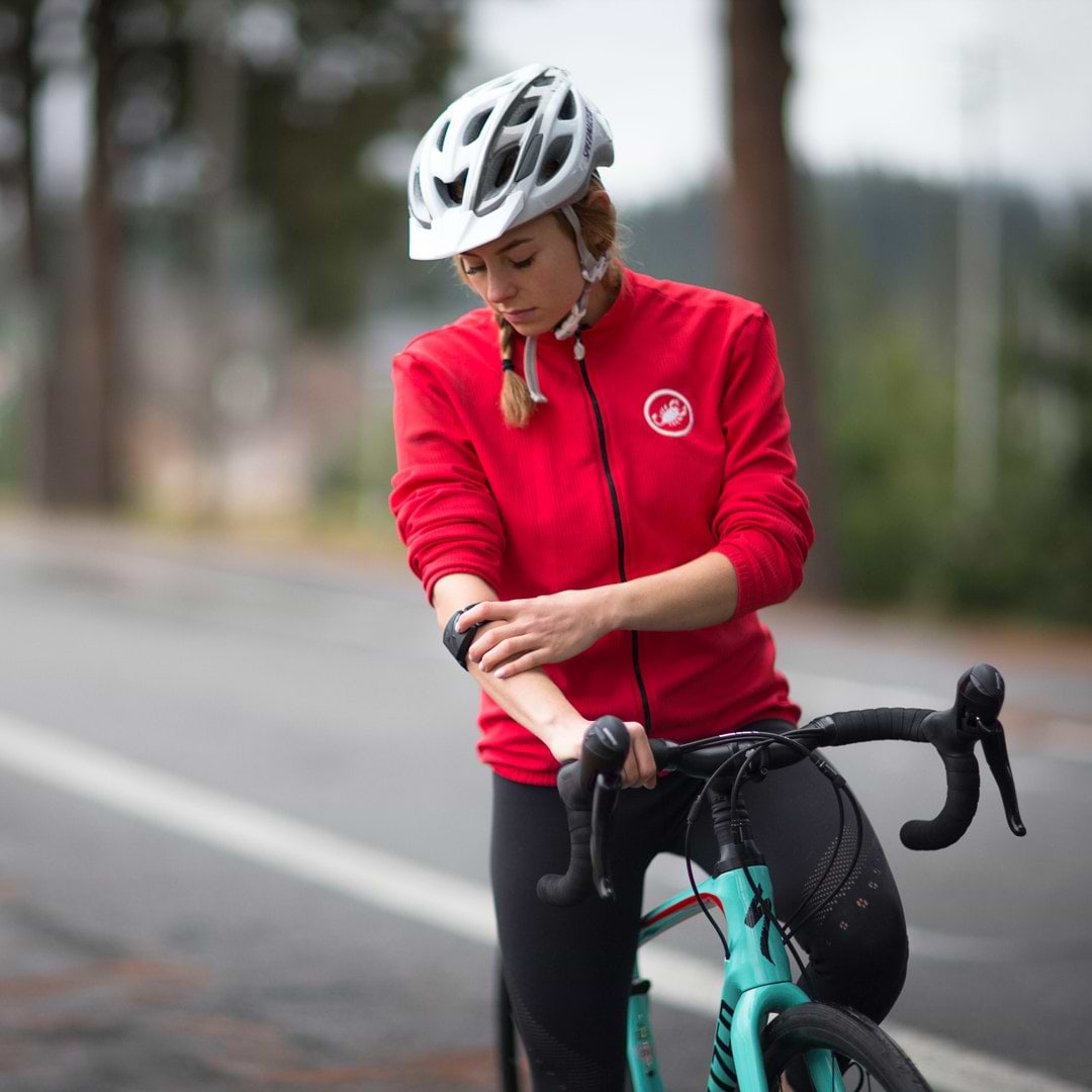 woman riding bike while checking armband heart rate monitor