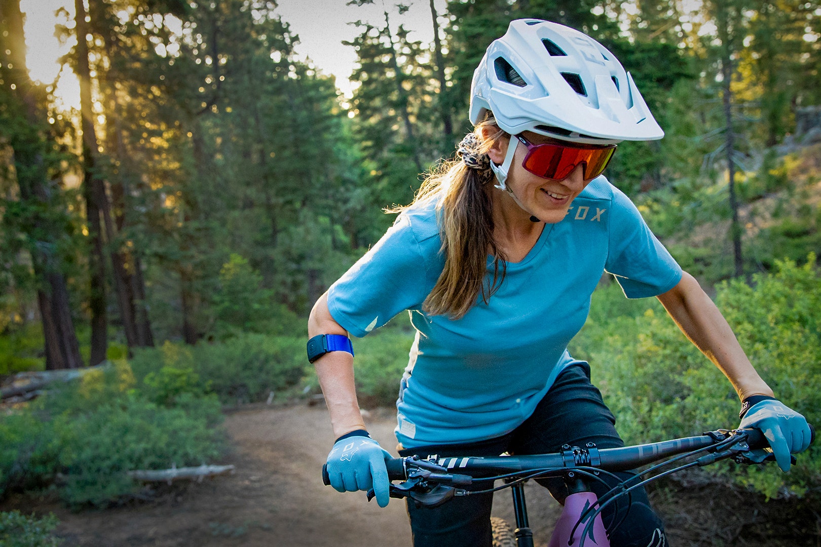 woman riding bicycle in forest wearing blue Rhythm heart rate monitor