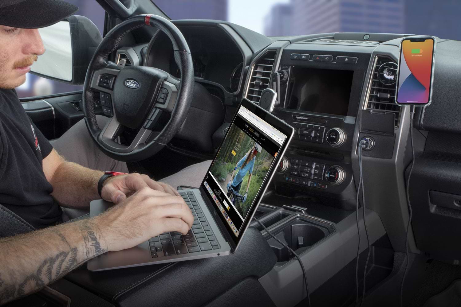 man using laptop while charging via Scosche dual port car charger and iphone charging while mounted to car vent
