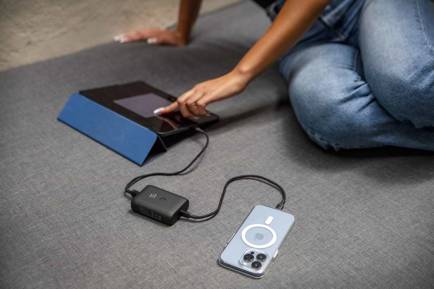 woman sitting on floor charging iphone and ipad via Scosche portable power bank