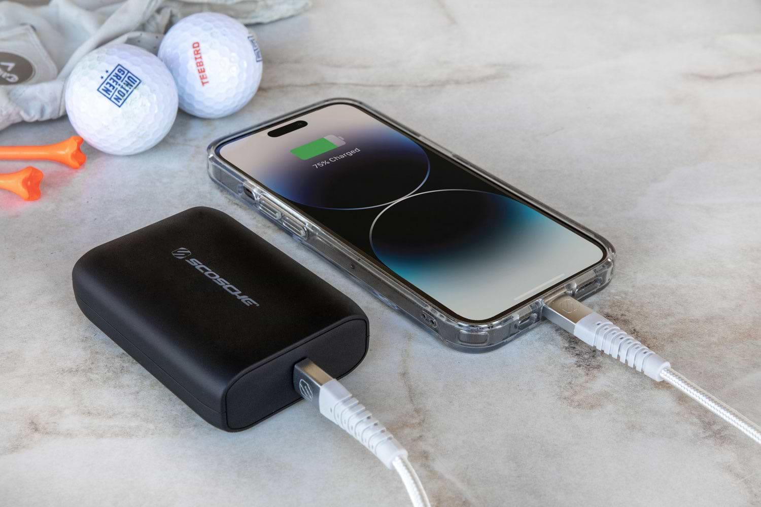 iPhone charging via Scosche portable power bank next to golf balls