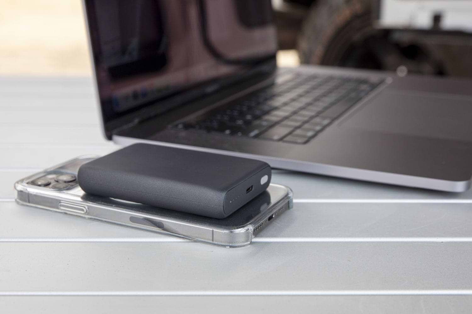iphone charging via MagSafe wireless power bank while sitting on table next to laptop