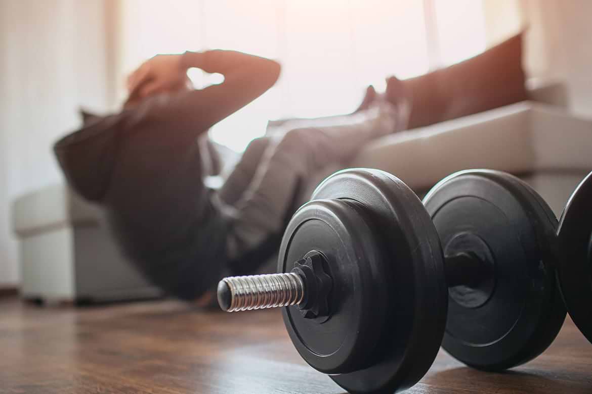 home exercise free weights with man doing sit ups in background