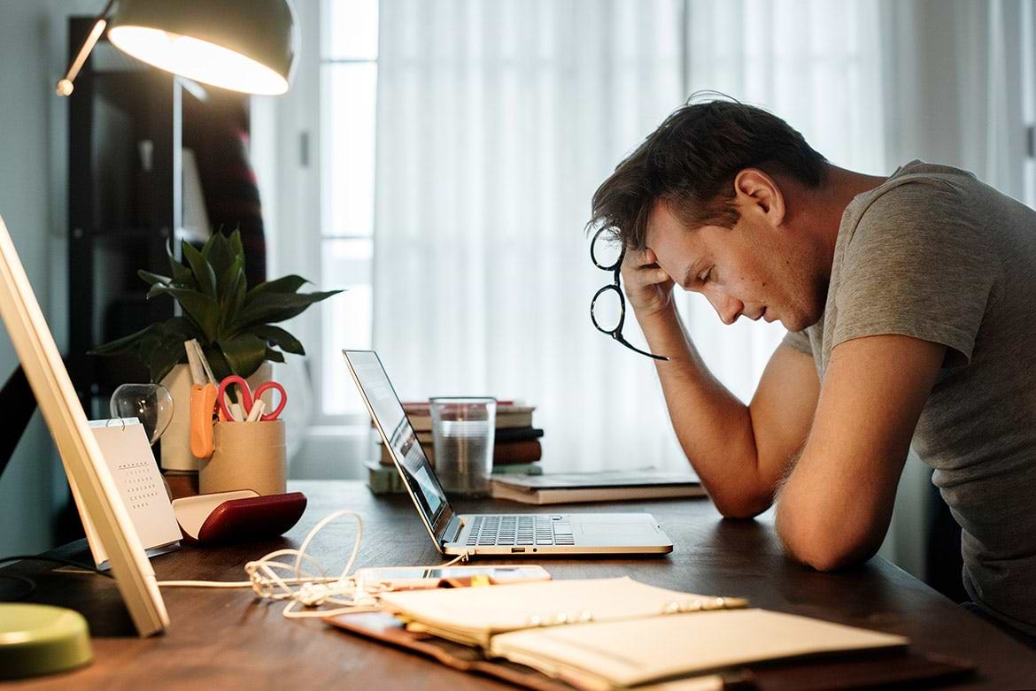 man stressed while working on laptop man stressed while working on laptop at desk