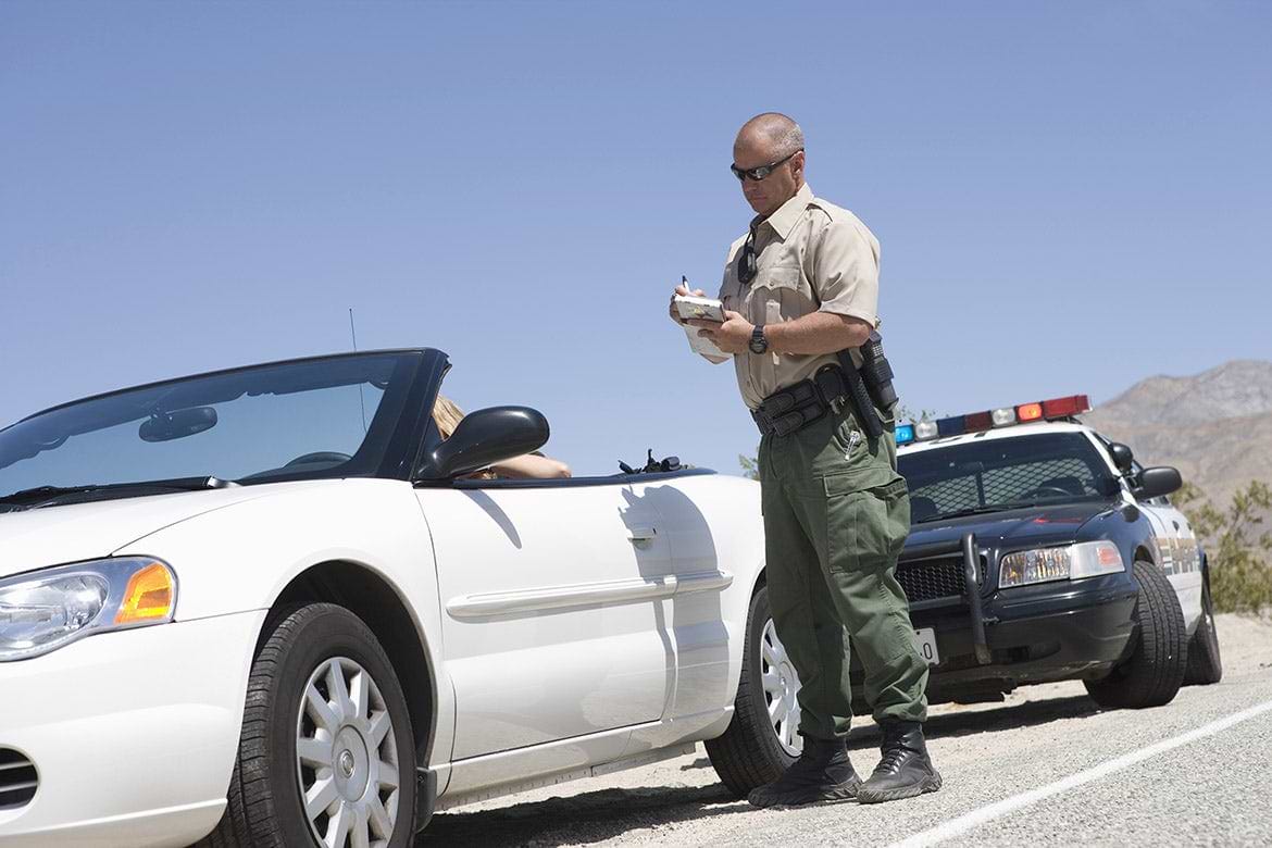 officer writing ticket officer writing ticket to woman in white car