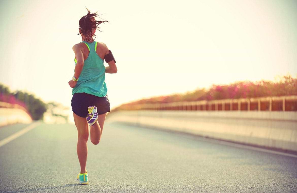runner back view of woman running on road