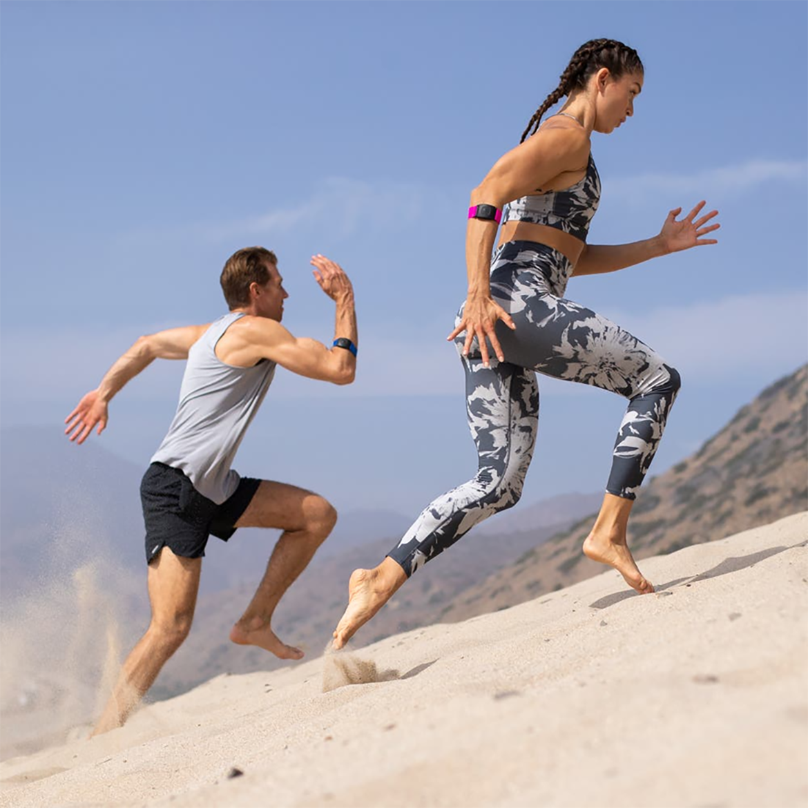 runners with heart rate monitor man and woman running uphill with heart rate monitor