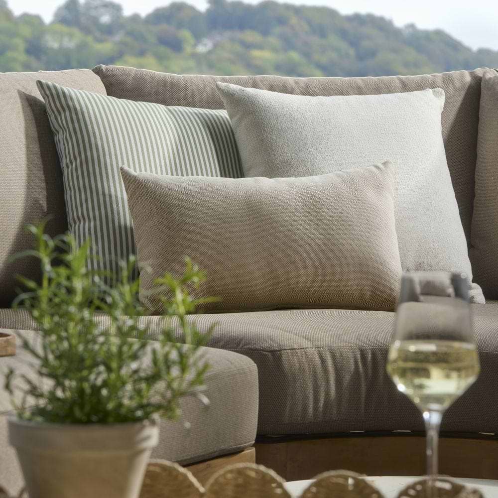 Neutral and striped outdoor cushions in a pile on an outdoor sofa.