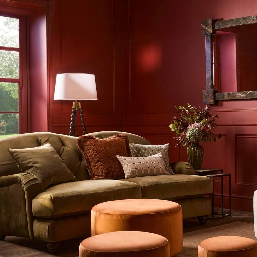 A green velvet sofa in a red painted living room