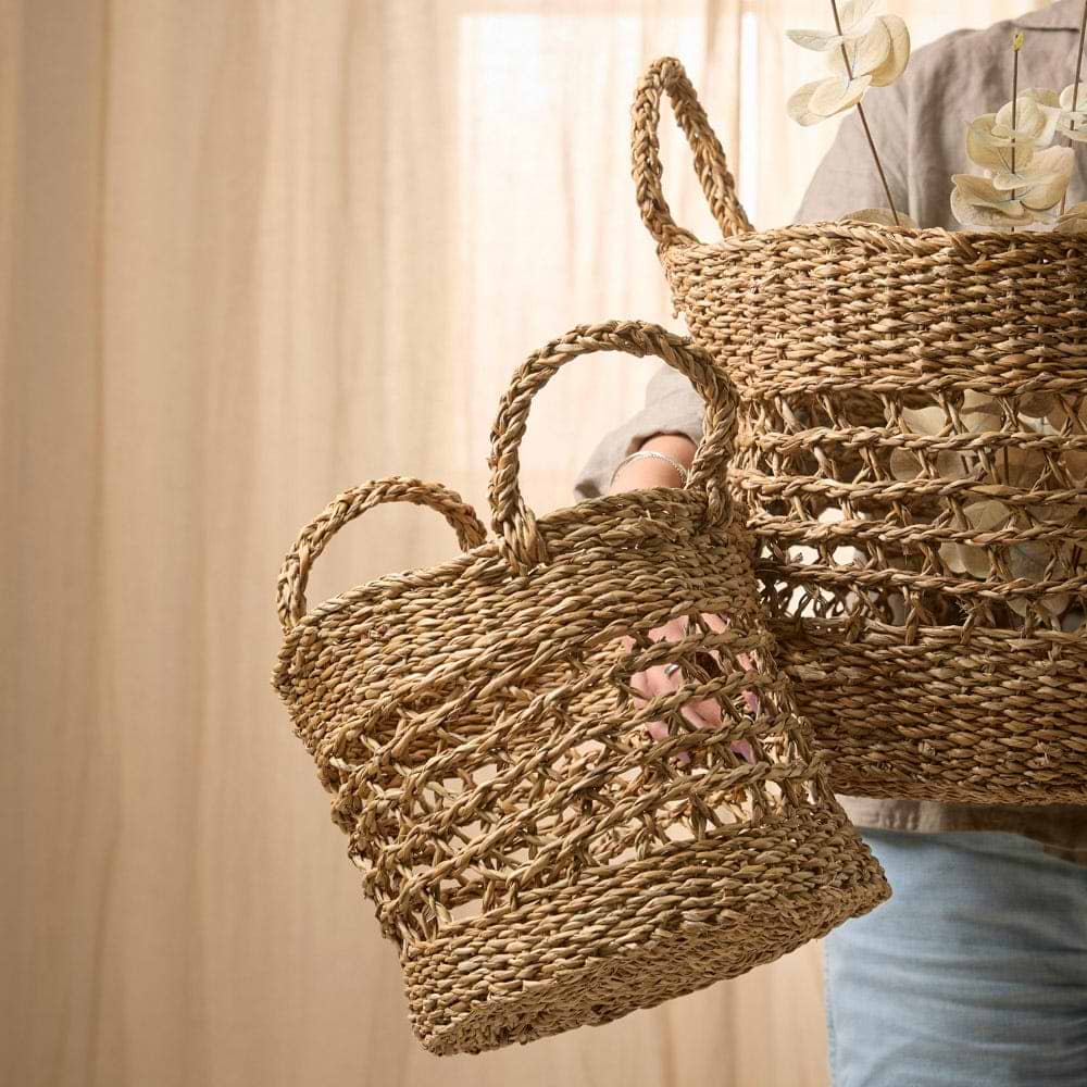Woman holding two seagrass baskets