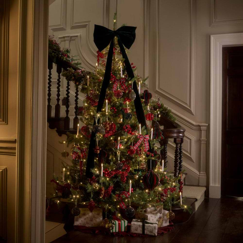 A hallway with a Christmas tree and dramatic staircase.