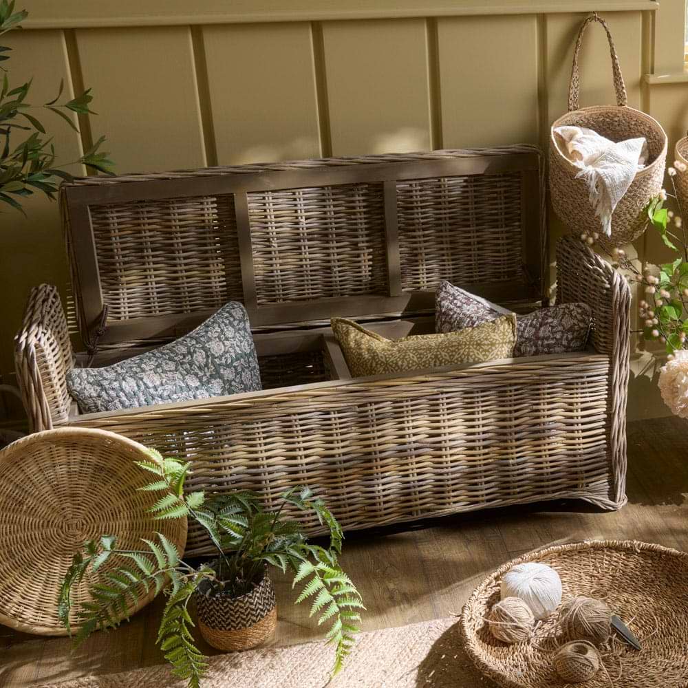 Rattan storage bench with lid up and filled with cushions