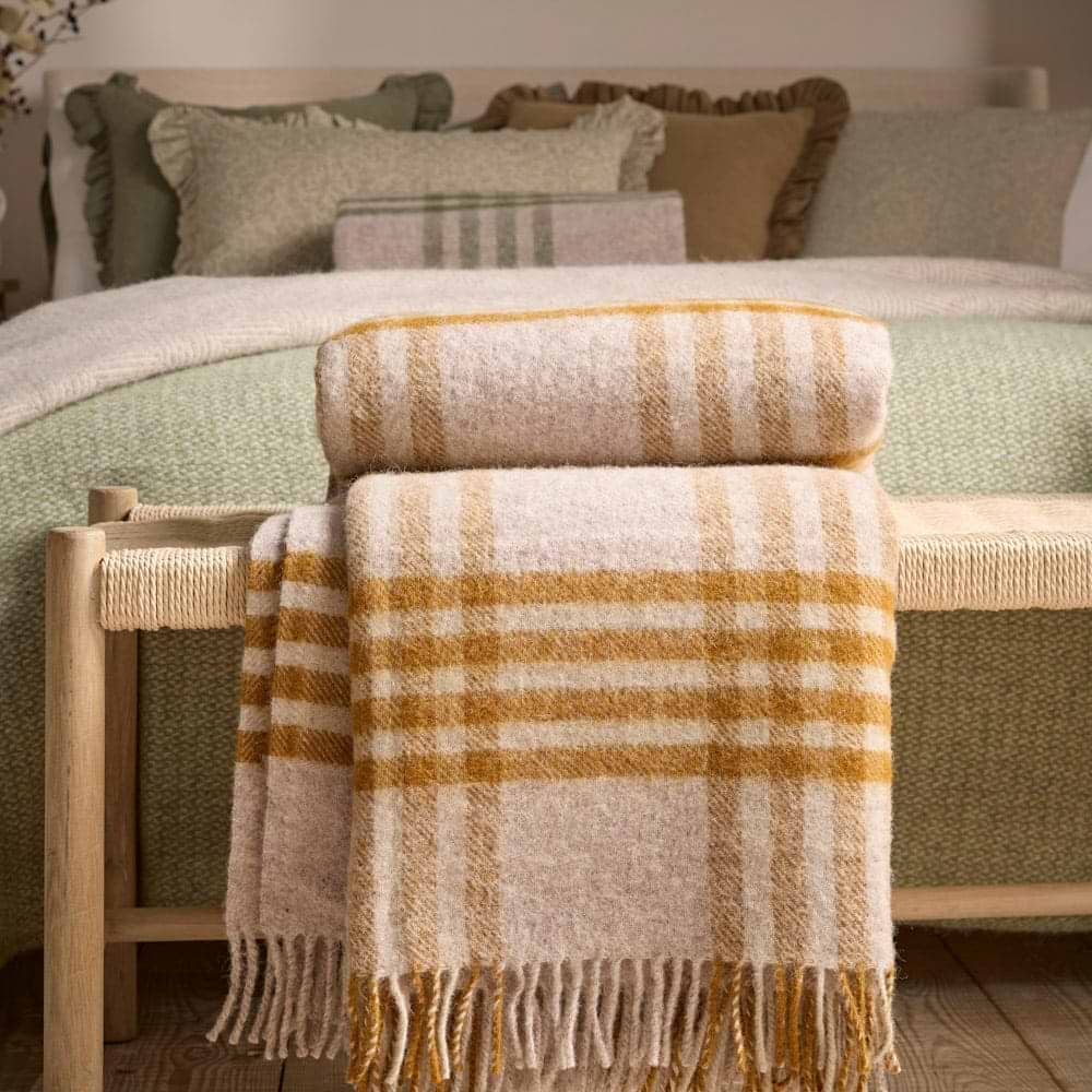 A pink and orange wool blanket at the end of a bed